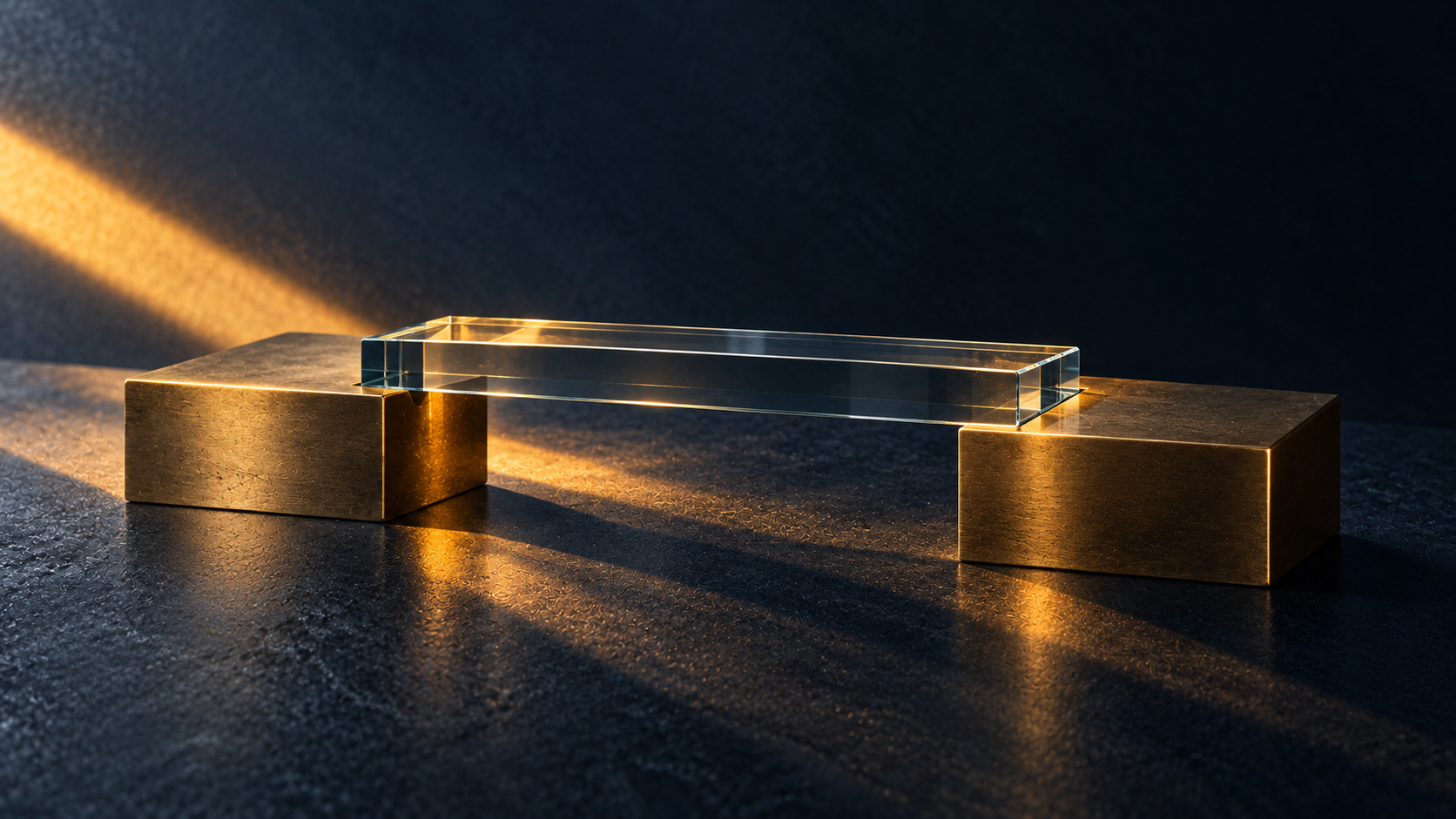 A transparent glass plate connects two brass supports on a dark surface.